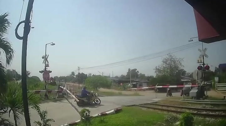 Bungling motorcycle rider clotheslined by level crossing barrier in Thailand