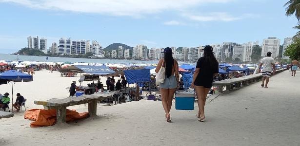 Pessoas levam cooler com comida e bebida para a praia, em Guarujá (SP)